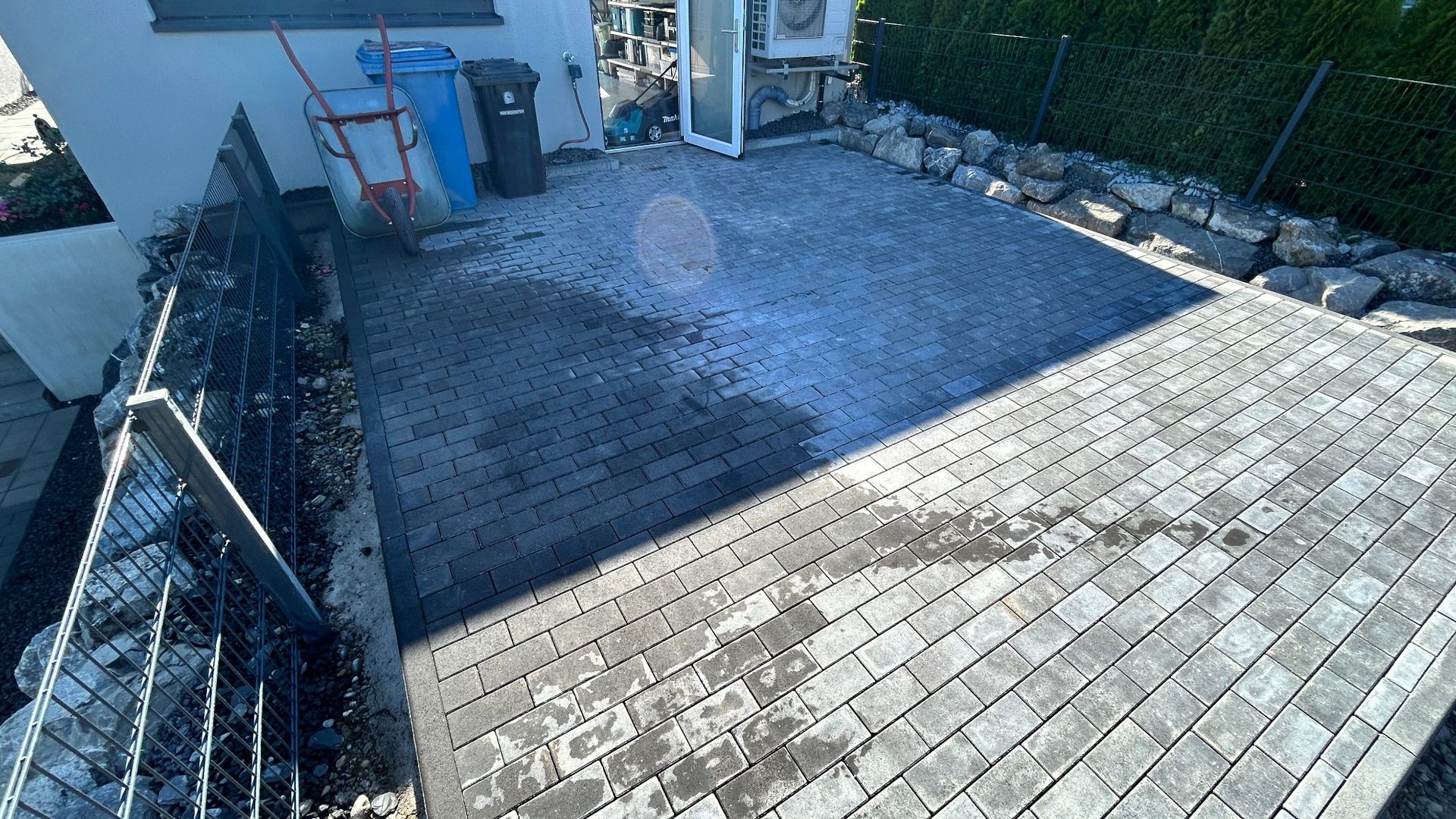 Fertig gepflasterte Fläche mit anthrazitfarbenen Pflastersteinen im Hofbereich.