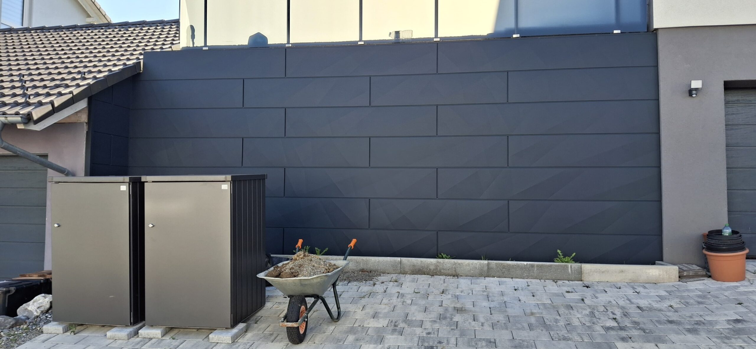 Moderne Fassadenverkleidung in anthrazitfarbener Optik an einem Wohnhaus.